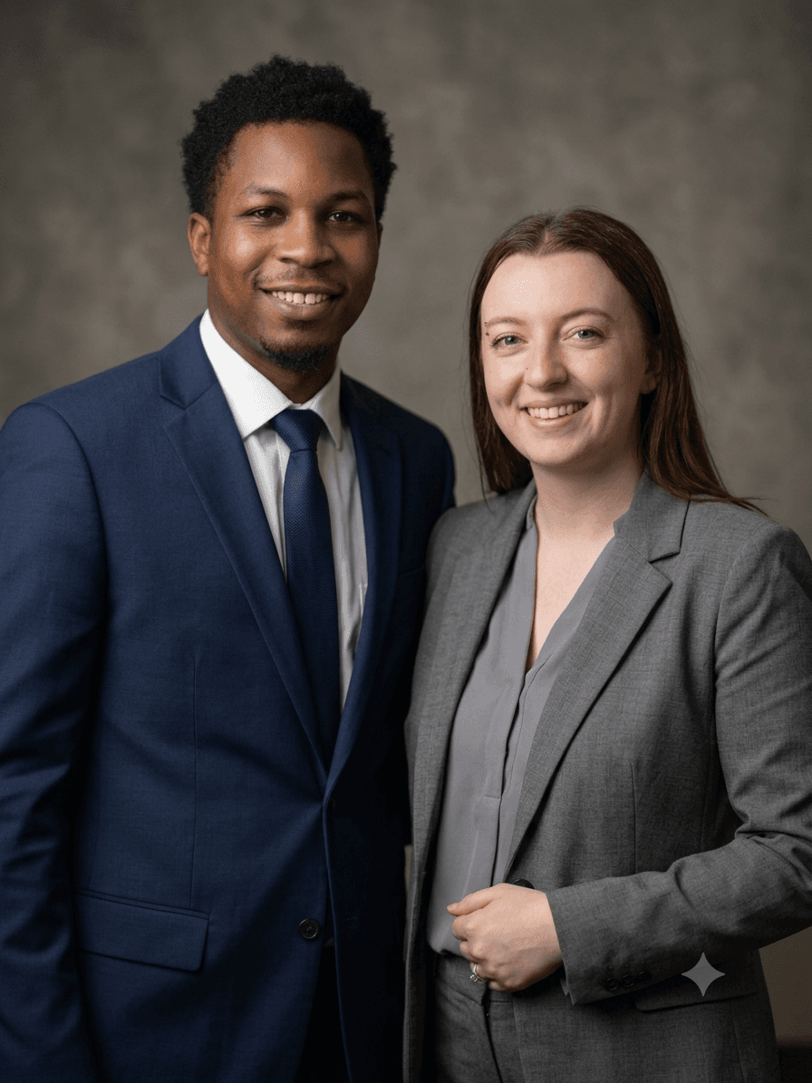 Smiling man in navy suit and woman in grey blazer posing for professional portrait.
